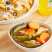 A bowl of Del Sol whole pickled jalapenos on a table next to a bowl of nachos.