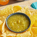 A plate of chips with Del Sol Salsa Verde on a table in a Mexican restaurant.