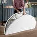 A man holding a Lancaster Table & Seating white plastic bi-folding table.