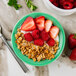 A Tuxton Cilantro China monkey dish filled with granola and strawberries.