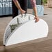 A man holding a Lancaster Table & Seating white plastic bi-folding table.