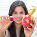 A woman holding a Pitaya Foods dragon fruit snack piece.