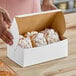 A person holding a white Southern Champion cake box full of pastries.