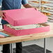 A person holding a pink Southern Champion bakery box with a white cake inside.