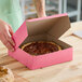 A person opening a Southern Champion pink pie box on a counter.