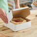 A person placing a pie into a Southern Champion bakery box.