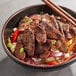 A bowl of Pulmuone Korean BBQ-Style Plant-Based Steak with meat and vegetables on a white background.
