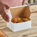 A person holding a white Southern Champion bakery box of cookies.