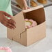 A person opening a Southern Champion cake box to reveal a cake with pink frosting.