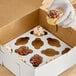 A hand putting a chocolate frosted cupcake with sprinkles in a Southern Champion cupcake box.