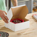 A person cutting a cake in a Southern Champion bakery box.