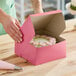 A person opening a pink Southern Champion cake box with a cake inside.