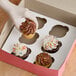 A hand places a cupcake with white frosting and sprinkles into a bakery box with a Southern Champion cupcake insert.