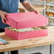 A man holding a pink Southern Champion bakery box with a cake inside.