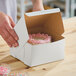 A person holding a Southern Champion white cake box with a cake inside.