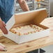 A person cutting a cake in a Southern Champion bakery box.