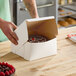 A hand opening a Southern Champion cake box on a counter.