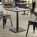 A Lancaster Table & Seating Excalibur table with a smooth square surface and square base plate.