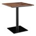 A Lancaster Table & Seating square table with a wooden top and black base plate.