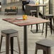 A Lancaster Table & Seating Excalibur square table with a textured wooden top.