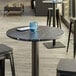A Lancaster Table & Seating wood table top with a smooth surface on a table with a blue drink.