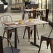 A Lancaster Table & Seating rectangular table with a textured mixed plank finish on a patio with chairs.