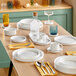 A table with white plates and Acopa Lore green highball glasses.