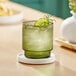 An Acopa Lore green old fashioned glass with a drink and a slice of lime.