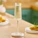 An Acopa Lore flute glass of champagne sits on a table.