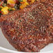 A piece of meat with Badia Table Grind Black Pepper and vegetables on a plate.