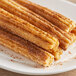 A plate of churros with cinnamon and sugar on a wood table.