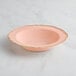 A pink Visions plastic bowl with gold vintage trim on a marble surface.