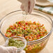 A person pouring Regal Cilantro into a bowl of food.