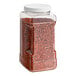 A plastic container of Badia Crushed Red Pepper with a red lid.