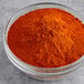 A bowl of Badia Cayenne Pepper powder on a gray surface.