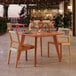 A Lancaster Table and Seating tigerwood table with wooden chairs on an outdoor patio.