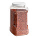 A plastic container of Badia Crushed Red Pepper with a red lid and red flakes inside.