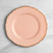 A Visions round plastic plate with blush pink and gold trim.