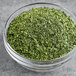 A bowl of Badia Parsley Flakes on a table.