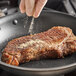A person sprinkling Badia ground white pepper on a piece of meat.