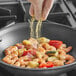 A person sprinkling Badia Lemon Pepper on a pan of food.
