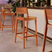 Lancaster Table & Seating Virelli Tigerwood slat back outdoor barstools at a table in a restaurant.