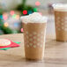 A brown beverage in a snowflake decorated plastic cup with whipped cream and snowflakes on top.