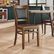 A Lancaster Table & Seating Sofia vintage wood chair with a vintage wood seat on a table in a restaurant dining area.