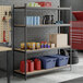 A black heavy-duty four-shelf boltless particle board shelving unit with 84-inch uprights, used for storage in a garage or workshop setting.
