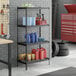 A black metal four-shelf boltless wire shelving unit with various automotive and cleaning supplies stored on it.