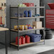 A black heavy-duty four-shelf boltless particle board shelving unit with 72-inch uprights, used for storage in a garage or workshop setting.