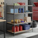 A black heavy-duty four-shelf boltless particle board shelving unit with 72-inch uprights, used for garage or workshop storage.