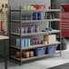 A black heavy-duty five-shelf boltless particle board shelving unit with various garage and automotive supplies stored on it.