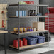 A black heavy-duty 4-shelf boltless shelving unit with particle board shelves and 84-inch uprights, used for garage or storage organization.